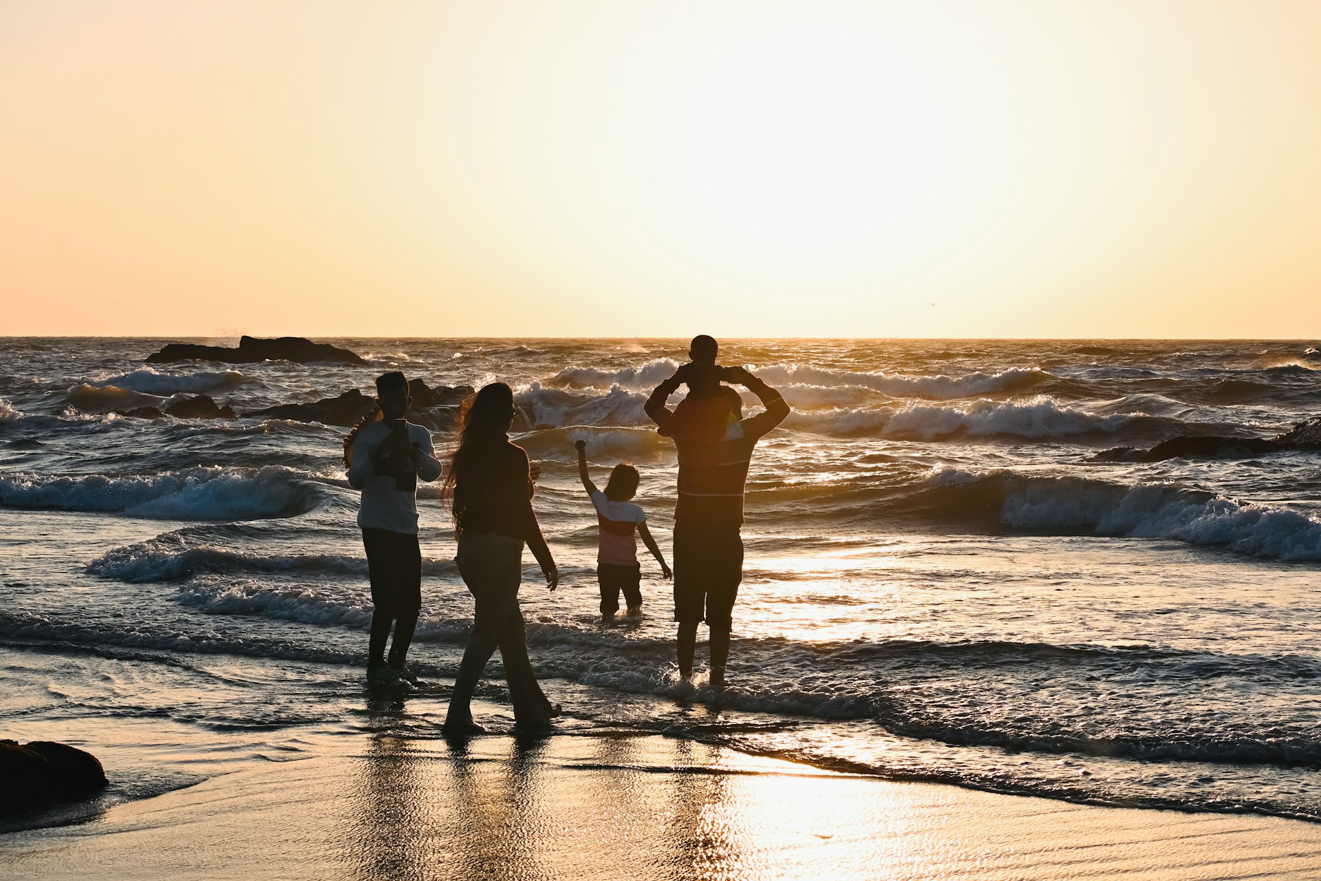A group of people standing on top of a beach next to the ocean